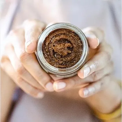Holding a jar of my 'Gulal' sugar and oats body polisher. This exfoliating scrub is gentle yet effective, helping to remove dead skin cells and reveal a healthy glow.