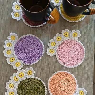 A set of my popular daisy coasters in various pastel colors. Each coaster has a solid center with a border of cheerful white and yellow flowers, perfect for a tea party.