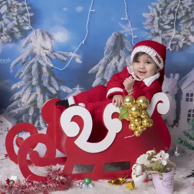 Your baby can be Santa's little helper in my Christmas themed photoshoot. This setup features a red sleigh, a Christmas tree, and a snowy winter backdrop.