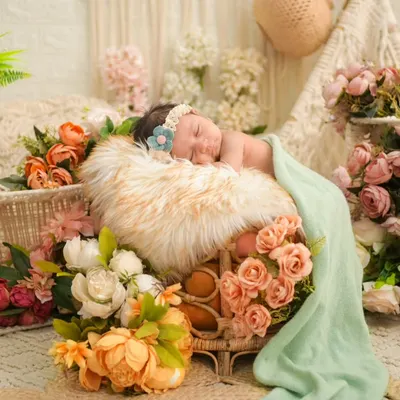 A newborn sleeps peacefully amidst a lavish arrangement of peach and white flowers. This floral-themed setup is one of our specialties, creating a dreamy, garden-like atmosphere for a truly enchanting portrait.