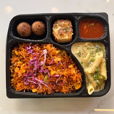 This meal box showcases our multi-cuisine capabilities, combining Continental and Oriental flavors. It includes creamy white sauce pasta, Mexican rice, cheese-topped garlic bread, and savory balls, offering a unique fusion experience.