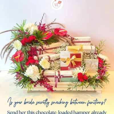 Is your bride secretly snacking between functions? Send her this chocolate-loaded hamper, beautifully arranged in a tiered wooden crate with red and white florals.