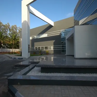 The primary entrance of the Komet India headquarters. A monumental white structural element frames the entry, creating a powerful first impression. The design uses clean lines and contrasting materials to establish a sophisticated corporate presence.