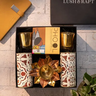 A classic Diwali hamper featuring Phool incense, patterned tumblers, and a brass lotus diya. This is a perfect example of a traditional yet elegant gift for clients and employees.