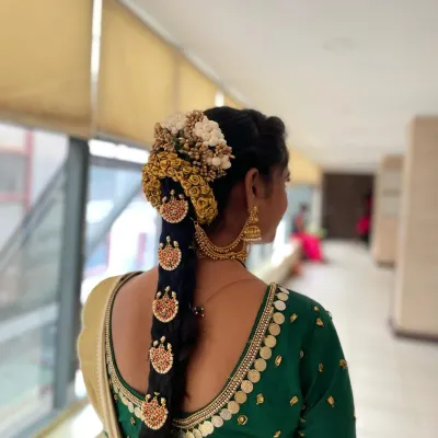 A stunning example of student work. This South Indian bridal hairstyle features a traditional long braid decorated with intricate temple-style jewelry, known as Jada Billalu, and a floral veni.