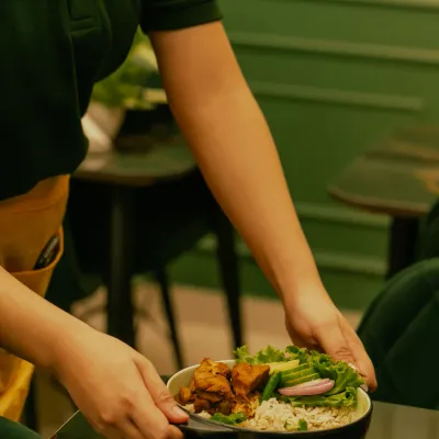 A staff member serving one of our popular 5-in-1 rice bowls, ready for you to enjoy.