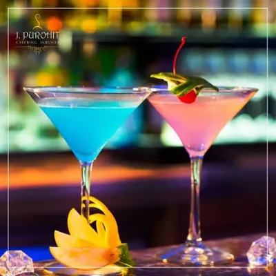 I believe a drink should be a centerpiece of your celebration. Here, two of my custom creations, a vibrant Blue Lagoon and a delicate pink mocktail, are served in classic martini glasses. The presentation, with artistic garnishes like a carved starfruit peel and a fresh cherry, reflects my commitment to making every detail perfect.