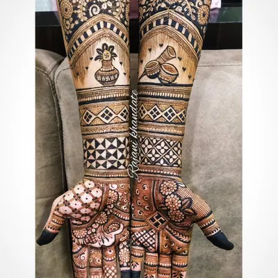 Mehndi for the groom. This design features full-arm coverage with traditional motifs like the 'kalash' and 'dhol', combined with modern geometric bands for a stylish and masculine look.