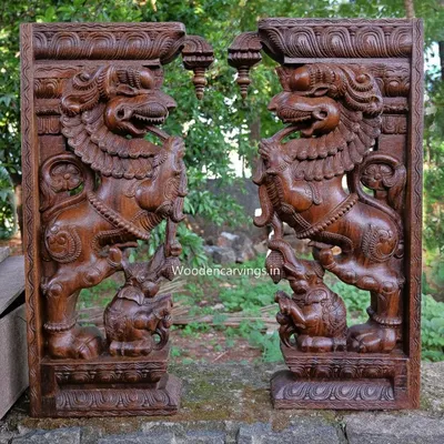 A pair of magnificent 36-inch Yaali brackets, carved in a rich wax brown finish. These mythical creatures, depicted subduing elephants, are powerful symbols often used in South Indian temple architecture.