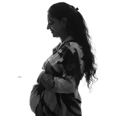 A beautiful high-key silhouette portrait. This black and white technique creates a striking and artistic image that emphasizes the profile and baby bump.