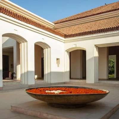 An 'urli' filled with marigolds sits at the heart of a sunlit courtyard, a traditional welcome that grounds the space in Indian heritage and offers a moment of peace.