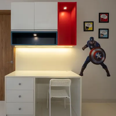 A study space fit for a superhero. This design features a clean white desk with drawers, overhead cabinets in red and blue, and a Captain America decal for a fun, personalized touch.