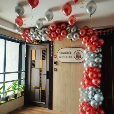 A simple and elegant balloon arch for a house entrance. This decoration in red and silver chrome balloons is a great way to welcome guests for a birthday or anniversary celebration at home.