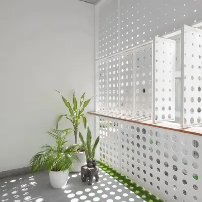The front facade features an operable perforated metal screen. This dynamic element creates an ever-changing pattern of light and shadow within the home while ensuring privacy from the street.
