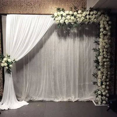 A simple and elegant backdrop featuring an L-shaped frame of white roses against a white curtain. This versatile design is perfect for engagements, receptions, or anniversaries.