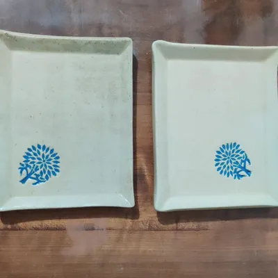 A pair of matching rectangular stoneware plates, perfect for serving appetizers or dessert. The simple, clean shape is decorated with a hand-stamped blue floral design, adding a pop of color to your table.