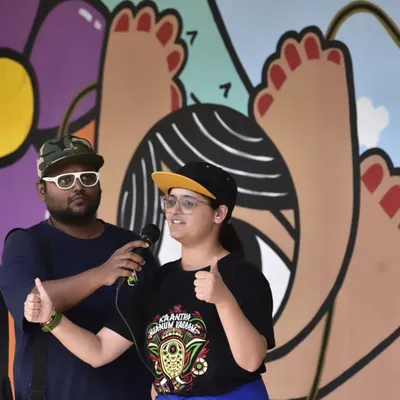 The power of sign language in action at Sign Fest 2024. An interpreter and a speaker share the stage, ensuring the message is accessible to everyone in our diverse audience. The vibrant mural behind them adds to the festive atmosphere.