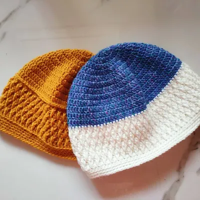 Two of my completed Sheldon beanies. This unisex hat pattern features a textured Alpine stitch panel and is shown here in mustard yellow and a blue and white combination.