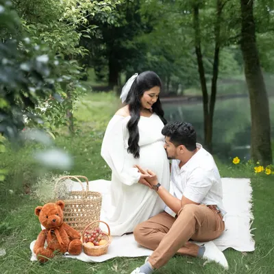 A romantic outdoor maternity session with a picnic setup by the water. This image captures the quiet anticipation and joy of expecting parents in a beautiful, natural setting.