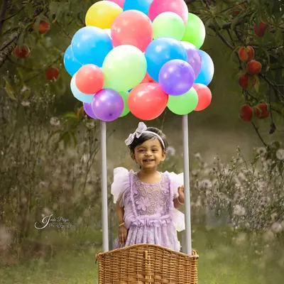 Up, up, and away! This hot air balloon prop creates a magical and whimsical scene for an outdoor birthday shoot, set against a beautiful green backdrop.