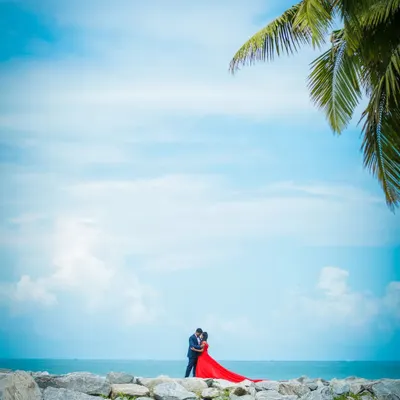 A breathtaking pre-wedding shot of a couple by the sea, with a vibrant red dress creating a stunning contrast against the blue sky. We specialize in creating epic, wide-angle shots at beautiful beach locations.