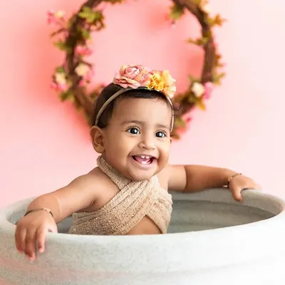 A bright, happy smile from a baby girl enjoying her milk bath session, a perfect and fun end to a first birthday photoshoot.
