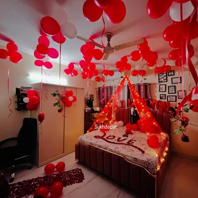 My signature romantic room decoration, featuring a full ceiling of red and white balloons, a fairy-lit bed canopy, and rose petals spelling 'LOVE' on the bed. This is the ultimate surprise for your partner.