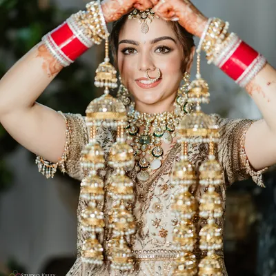 A classic bridal shot of a Sikh bride proudly showing off her beautiful 'kalire', a symbol of her new journey.