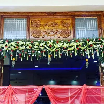 A beautifully crafted traditional garland to adorn the entrance of a home or venue. This design uses woven coconut leaves, red roses, and baby's breath for a welcoming and auspicious look.