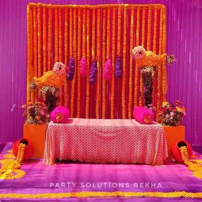 A perfect stage for a Haldi ceremony, glowing with tradition. I used a backdrop of dense marigold strings, accented with purple and pink, and quirky bird motifs made of flowers to create a truly unique and colorful setting.