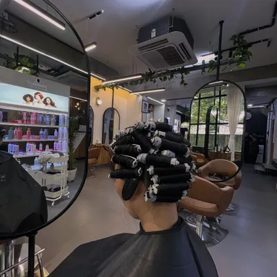 This is a behind the scenes look at the perming process. I carefully wrap sections of hair around perm rods, which is a crucial step to determine the size and shape of the final curls.