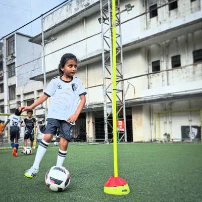 A player practices her dribbling technique around a training pole. These drills are designed to improve close control and agility, essential skills for any football player.