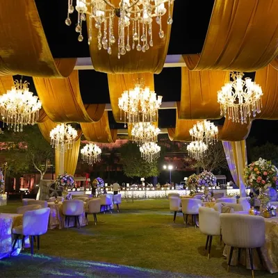 A sky full of stars and chandeliers. For this 'Golden Grandeur' reception, we created a breathtaking ceiling with flowing golden drapes and dozens of crystal chandeliers, making the outdoor space feel magical.