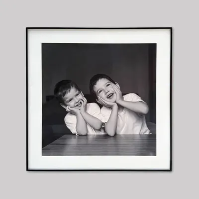 A cherished memory of childhood, framed with timeless simplicity. We used a sleek black metal frame and a crisp white mount to let the joy in this black and white photograph shine through.
