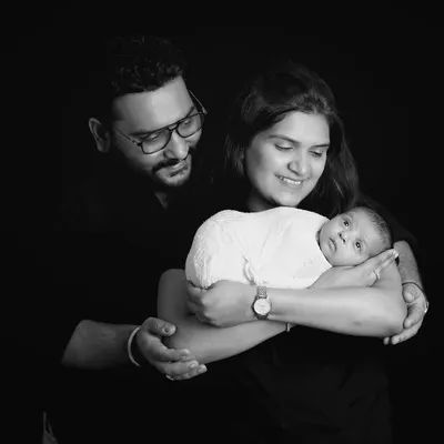 A classic family portrait in black and white. The dark background makes the family the sole focus, highlighting their loving embrace and connection.
