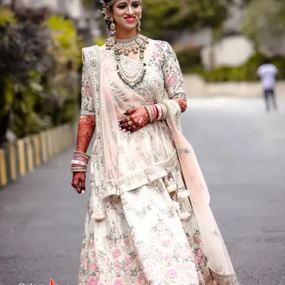 A full-length portrait of a stunning bride in her intricately embroidered floral lehenga, looking absolutely radiant on her wedding day.