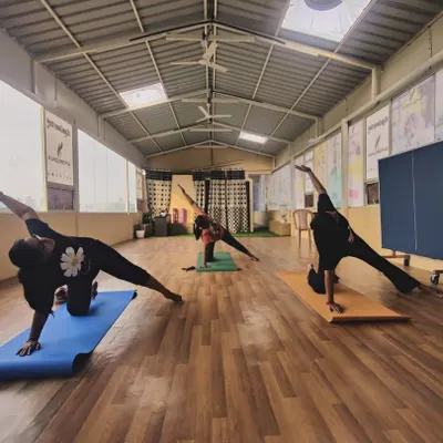 In our group Hatha yoga sessions, we focus on building foundational strength and stability. Here, our students practice a variation of Vasisthasana (Side Plank Pose), engaging their core and improving balance in our sunlit studio.