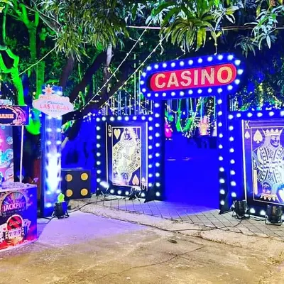 A complete outdoor entrance for a casino night party. The setup includes a large "Casino" marquee sign, themed gates, and a "Bank" booth, all lit up to create an exciting nighttime atmosphere.
