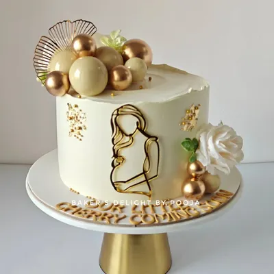 A sweet beginning. This elegant baby shower cake in white and gold is a beautiful way to celebrate a mom-to-be. The simple line art and cascading chocolate spheres create a modern and sophisticated look.