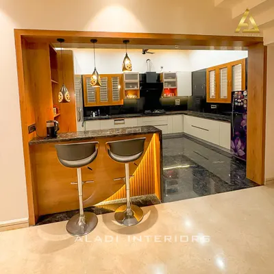 This open-plan kitchen features a custom breakfast bar with integrated lighting and wood paneling, seamlessly connecting to the main kitchen area.