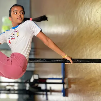 Strength, grace, and determination. This student holds a strong position on the bar, a fundamental piece of equipment for building the upper body and core strength needed for gymnastics.