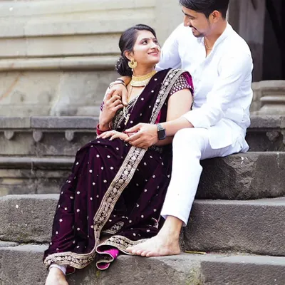 A beautiful moment between a couple in traditional attire. The bride-to-be looks stunning in a deep purple velvet Navari saree, perfect for a pre-wedding shoot.