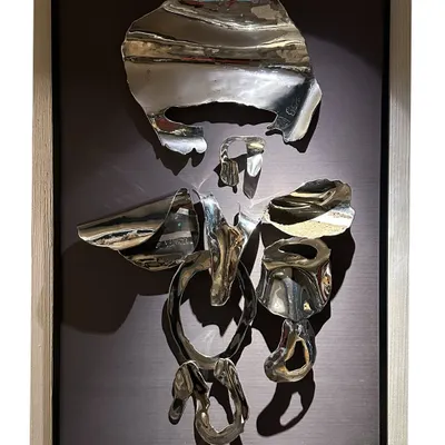 An abstract Ganpati crafted from fragments of polished stainless steel, mounted in a frame. This piece symbolizes strength, resilience, and new beginnings, deconstructing the form to its essential spiritual energy.