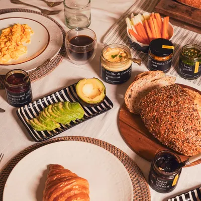 A beautiful breakfast spread to start your day right. Featuring a fluffy croissant, scrambled organic eggs, sliced avocado, and our artisanal house-made dips and preserves with freshly baked bread.