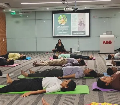 Guiding employees at ABB through Savasana, or corpse pose, at the end of a corporate yoga session. This final relaxation is crucial for integrating the practice and reducing stress.