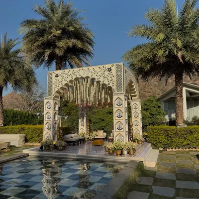 A wide view of our Rajasthani-inspired mandap, perfectly situated by a checkered pool and framed by palm trees at the Taj Aravali in Udaipur.