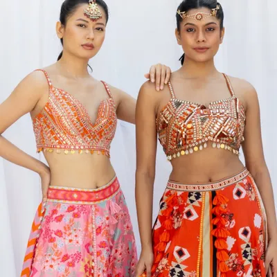 A fashion-forward shot for a designer lookbook. This image focuses on the modern, embellished blouses and vibrant lehengas, perfect for a sangeet or cocktail event.