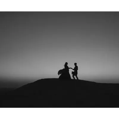A dramatic silhouette in the Dubai desert. This black and white frame captures the timeless and epic nature of love, with the wind and sand creating a cinematic, movie-like moment.