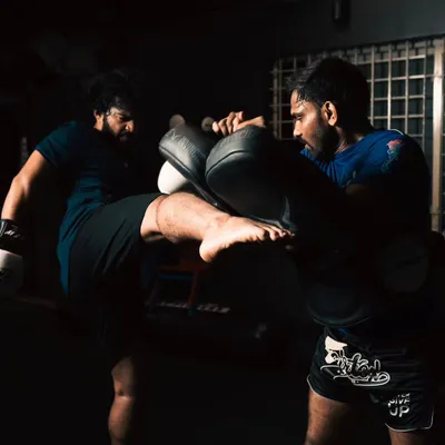Power generated from the ground up. A student practices a roundhouse kick on the pads, focusing on hip rotation and impact.