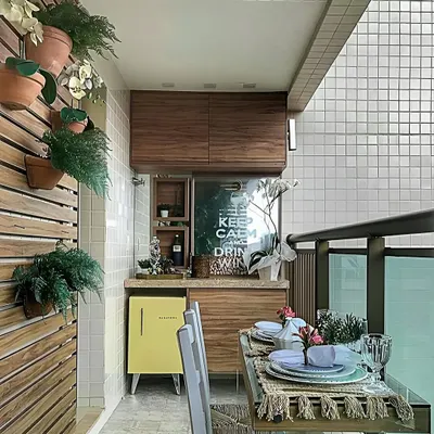 This compact balcony was transformed into a functional dining and bar area. The design includes a custom wooden cabinet with a mini-fridge, a wall-mounted bar, and a small dining table, proving that even small spaces can be highly functional.